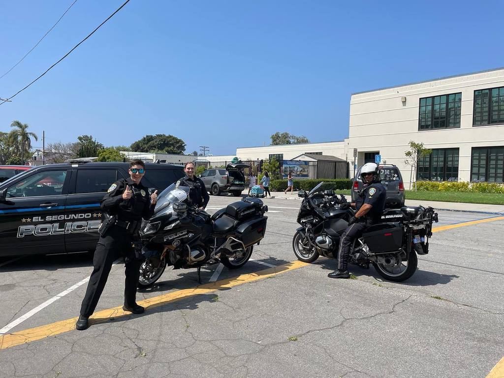 El segundo police officers giving a thumbs up in the parking lot